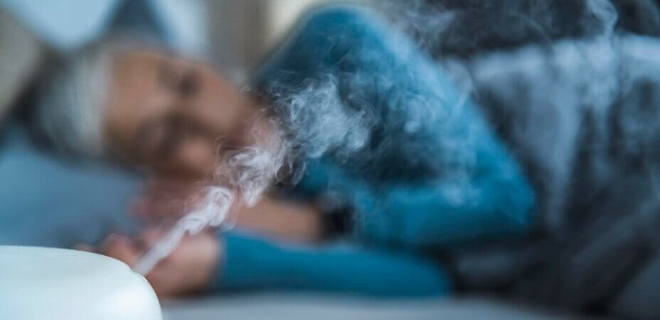 Kobieta śpiąca z włączonym nawilżaczem powietrza w celu poprawy wilgotności powietrza w sypialni