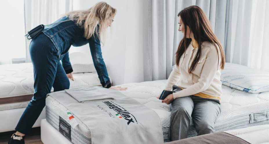 Kobiety testujące twardość materaca piankowego Magniflex w salonie