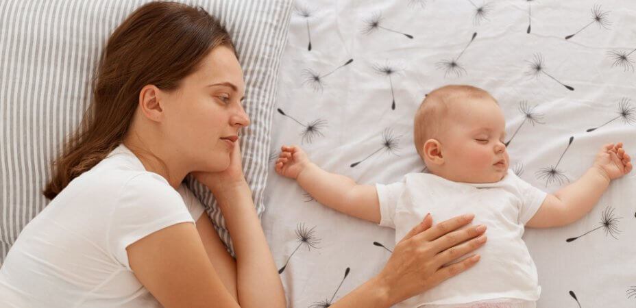 mama głaszczące niemowlę do snu