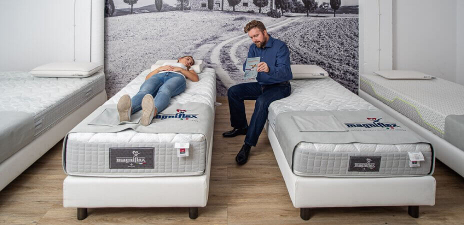 Kobieta z doradcą w Showroom testująca materace Magniflex