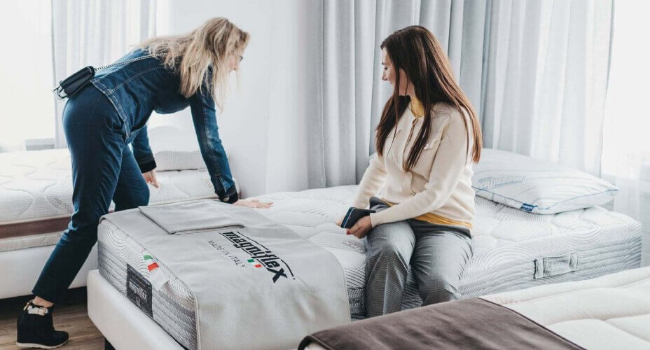 Kobiety testujące materac Magniflex i jego twardość w salonie materacy